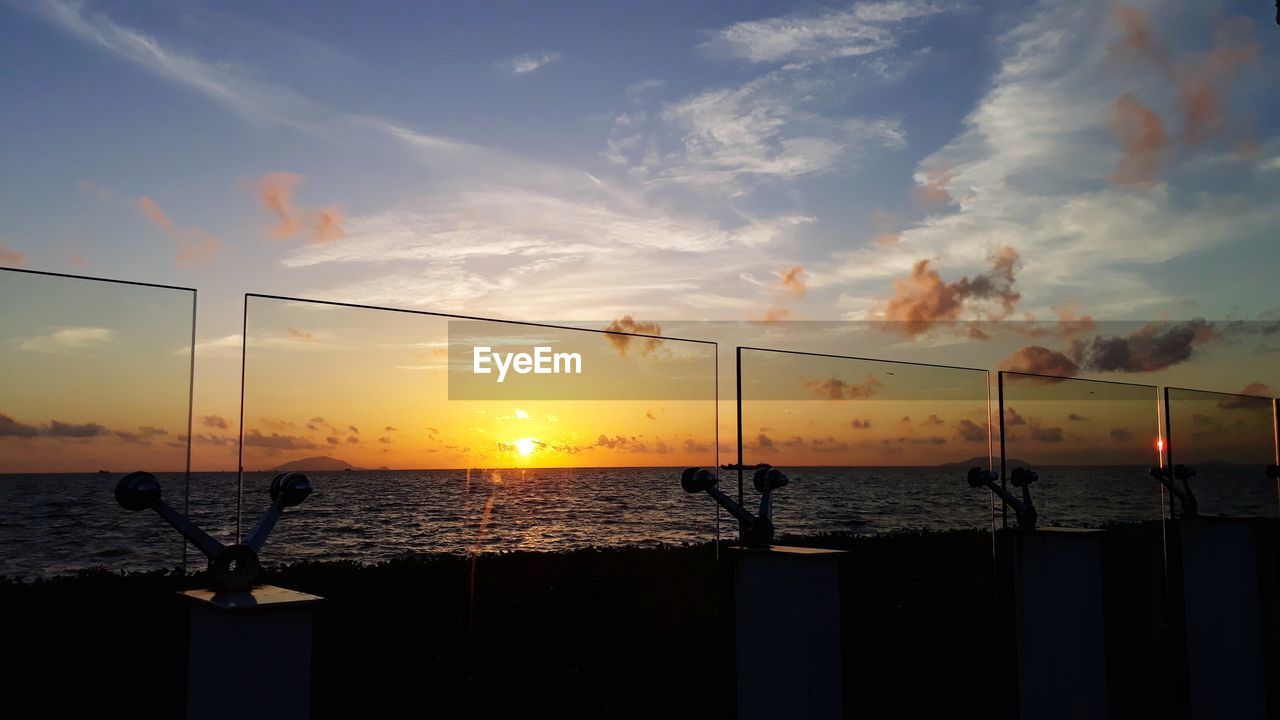 SILHOUETTE WOODEN POSTS IN SEA DURING SUNSET