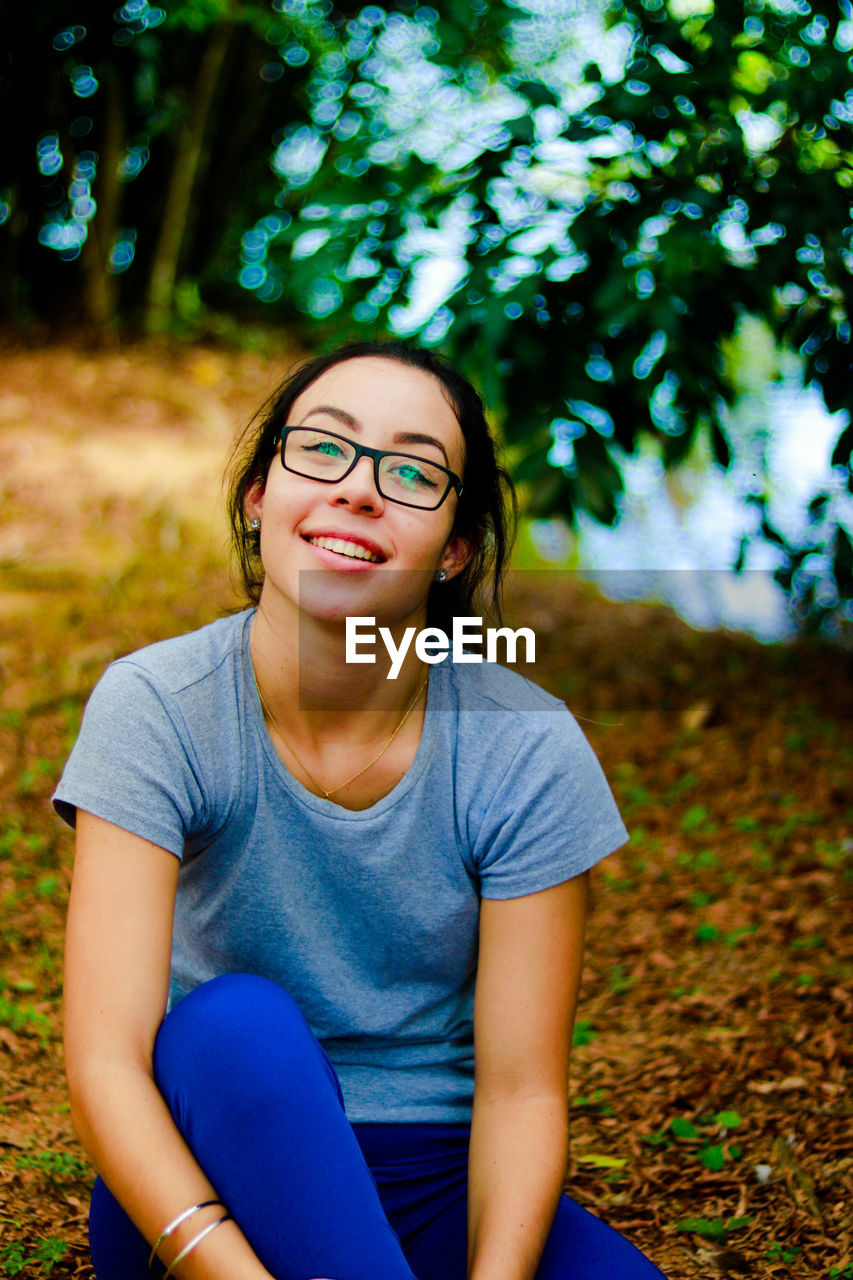 Portrait of smiling young woman sitting on field in park