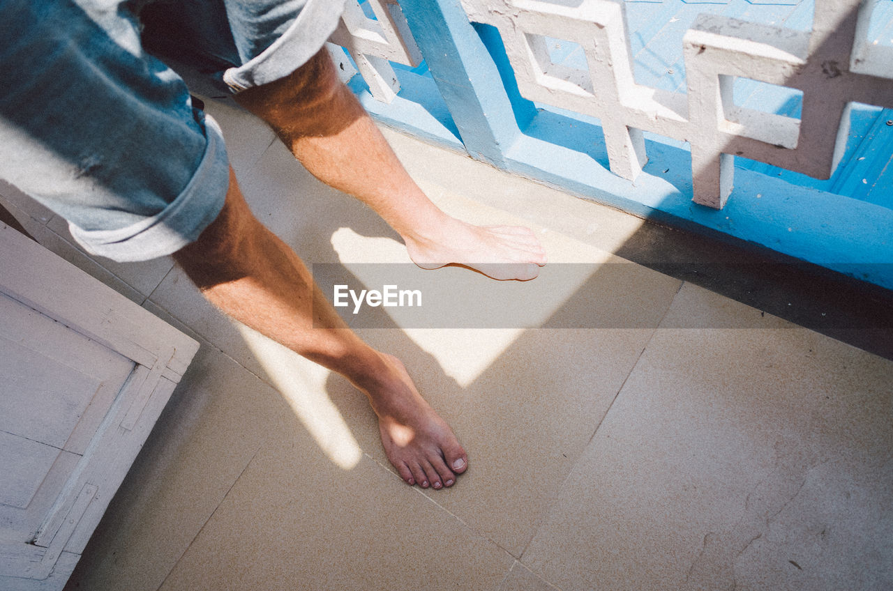 Low section of man standing by railing in balcony