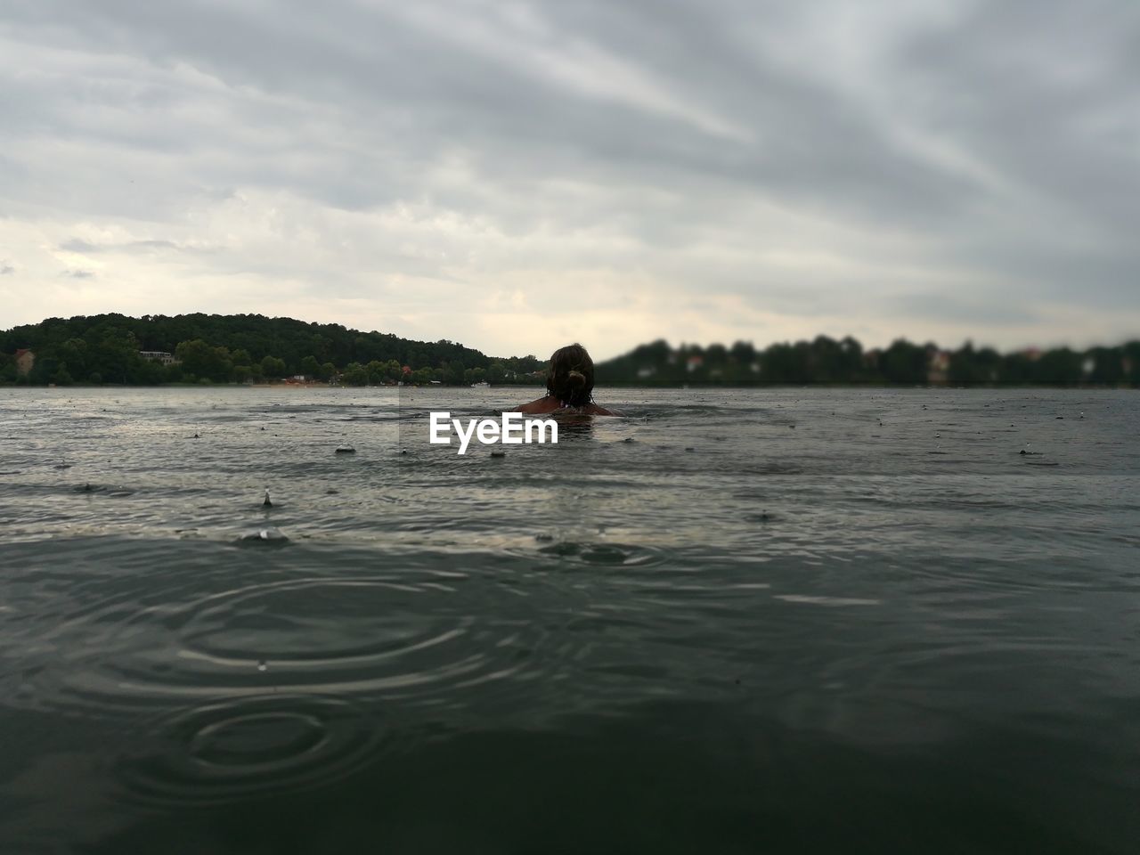 Rear view of woman in lake during rainy season