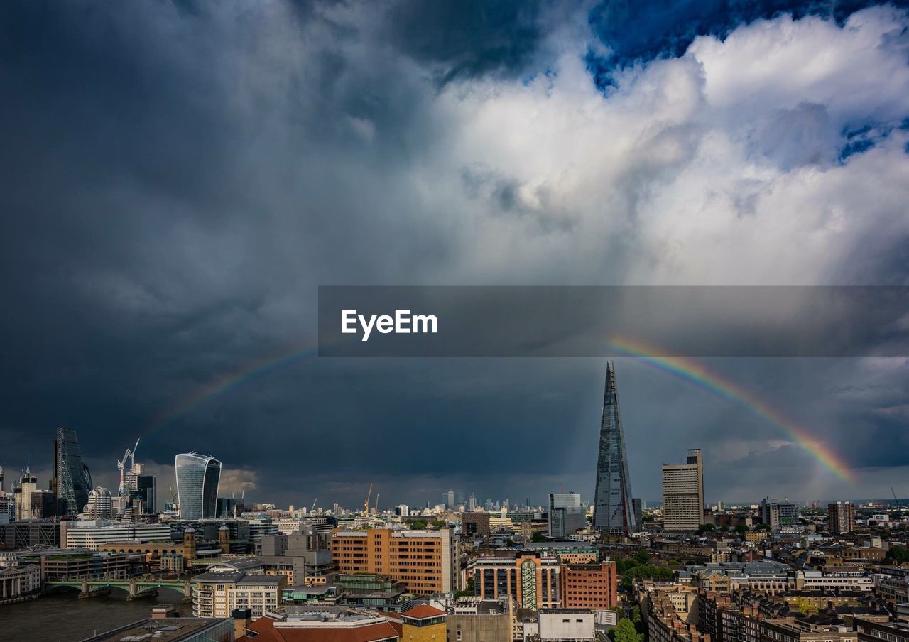 View of rainbow over city against cloudy sky