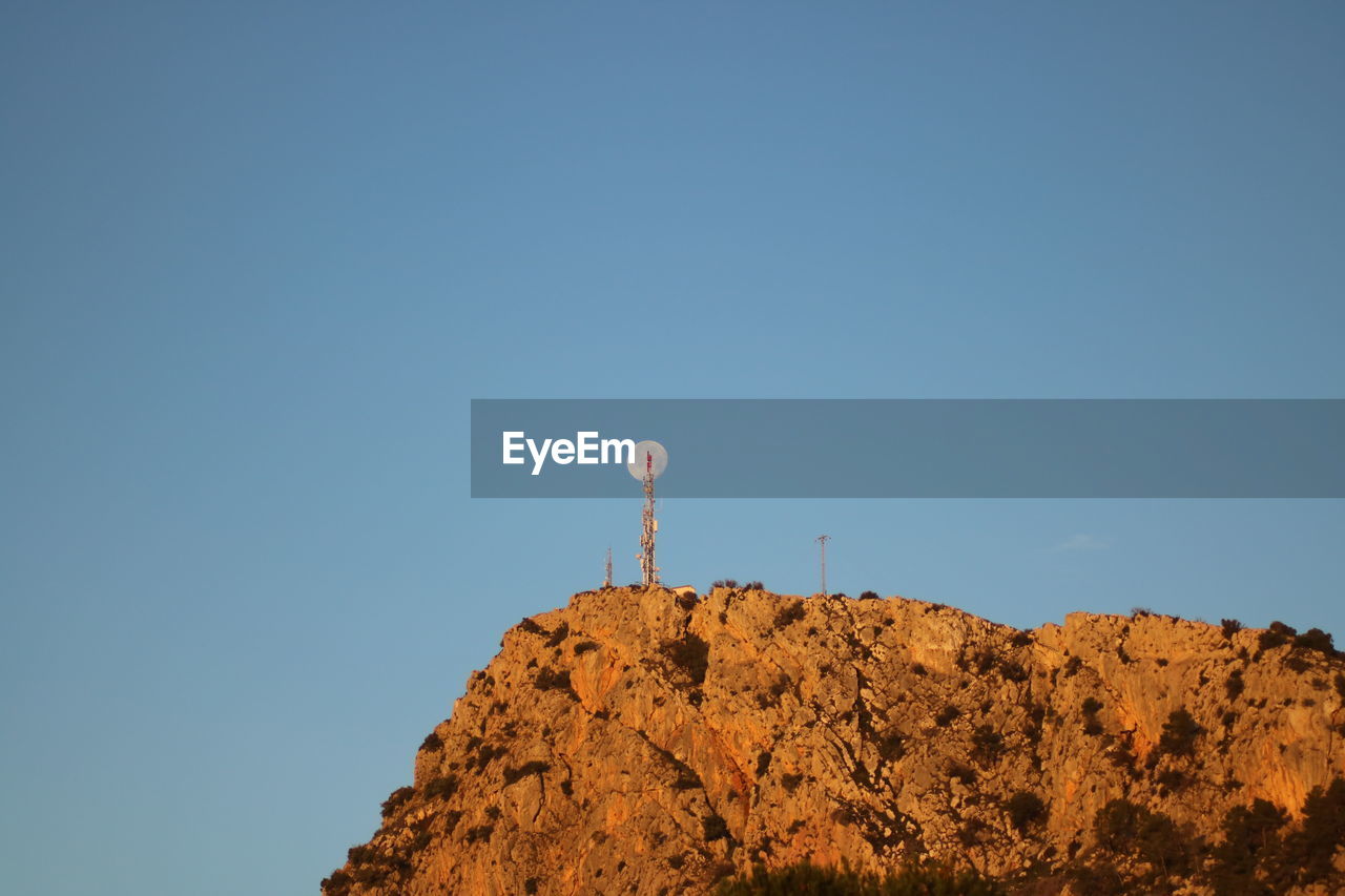 Low angle view of rocks against clear blue sky