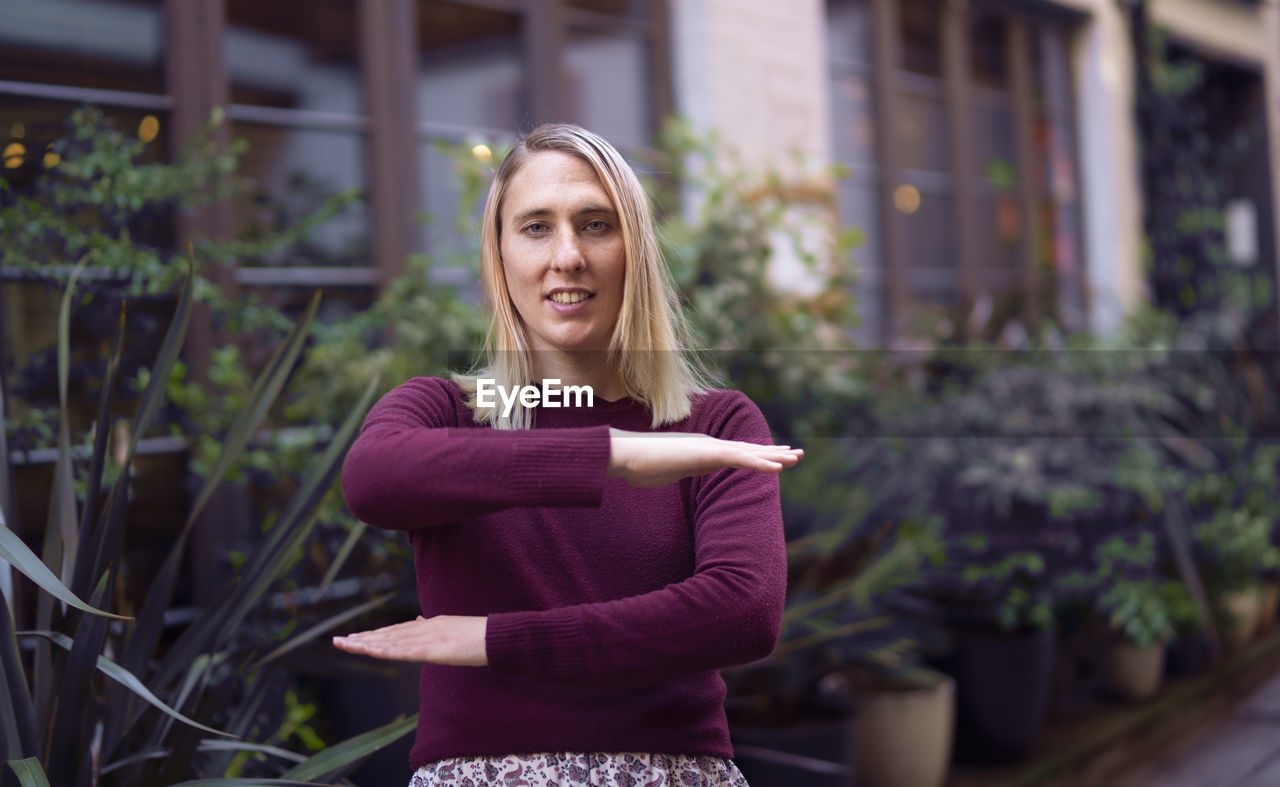 Portrait of woman gesturing while standing against plants