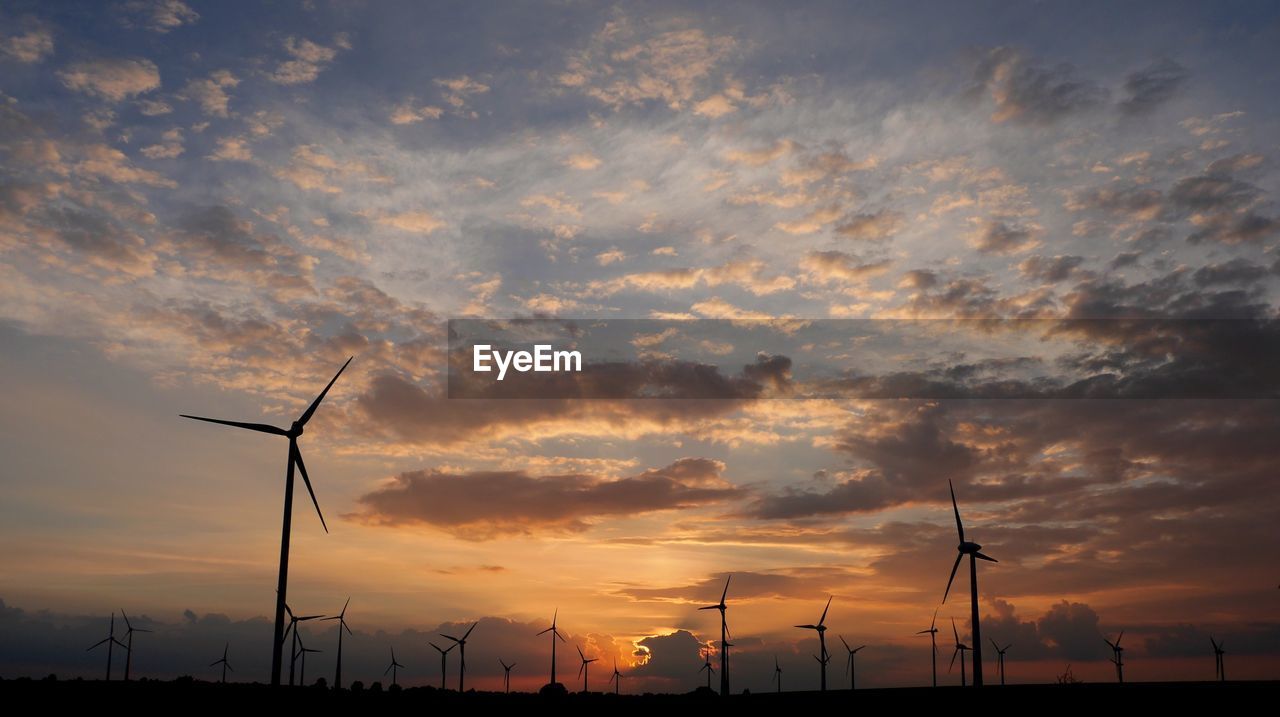 Wind turbines on landscape against sky