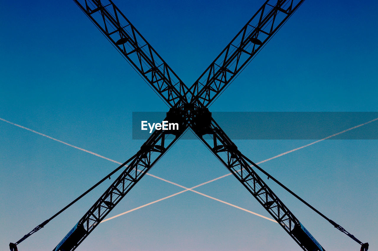 Low angle view of crane against clear blue sky