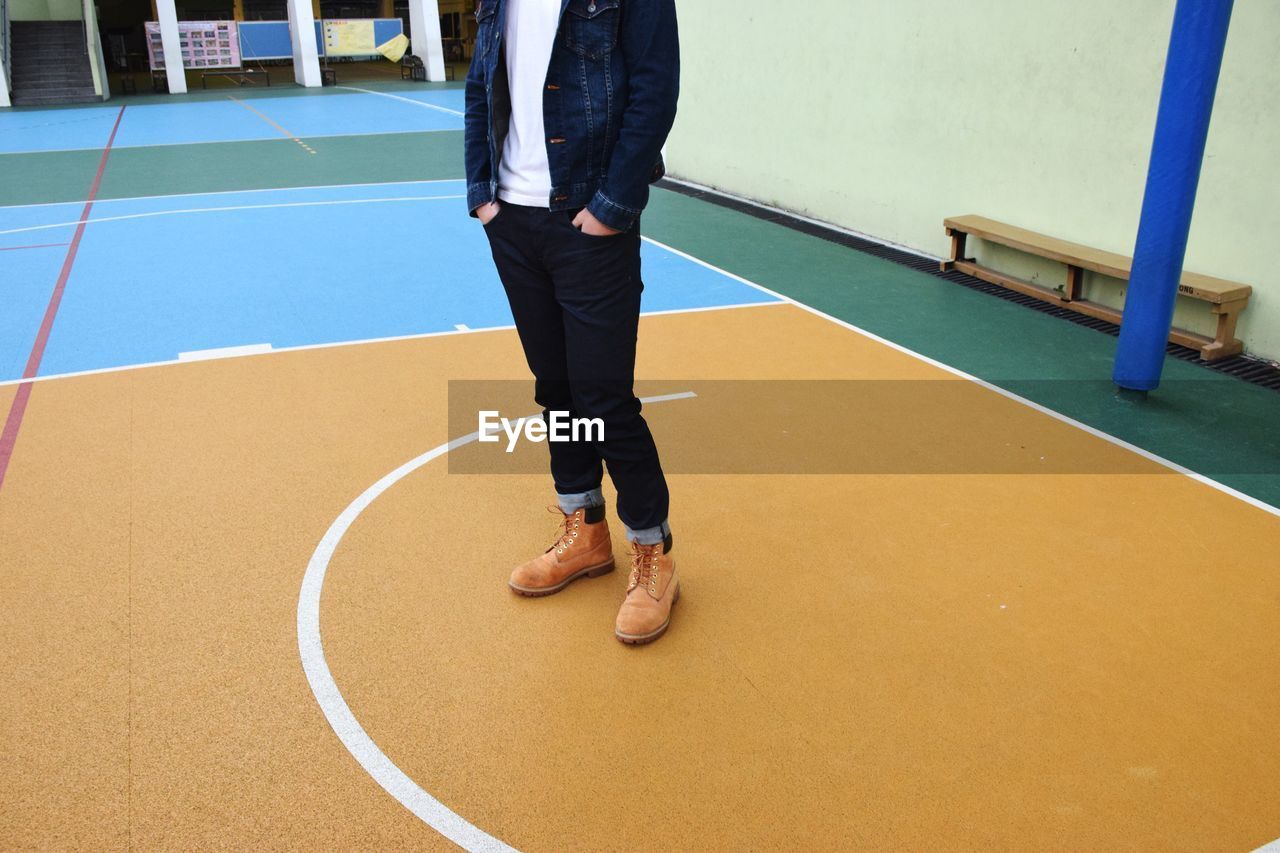 LOW SECTION OF MAN STANDING WITH UMBRELLA ON FLOOR