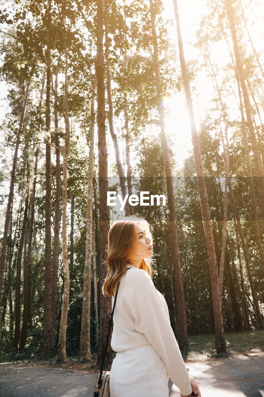 Side view of woman standing in forest