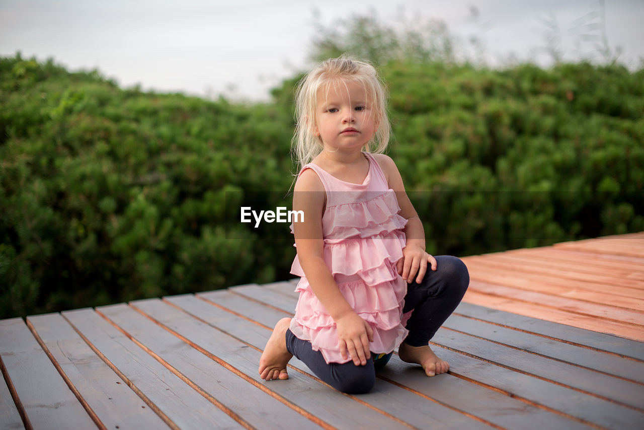 Full length portrait of cute girl kneeling on floorboard