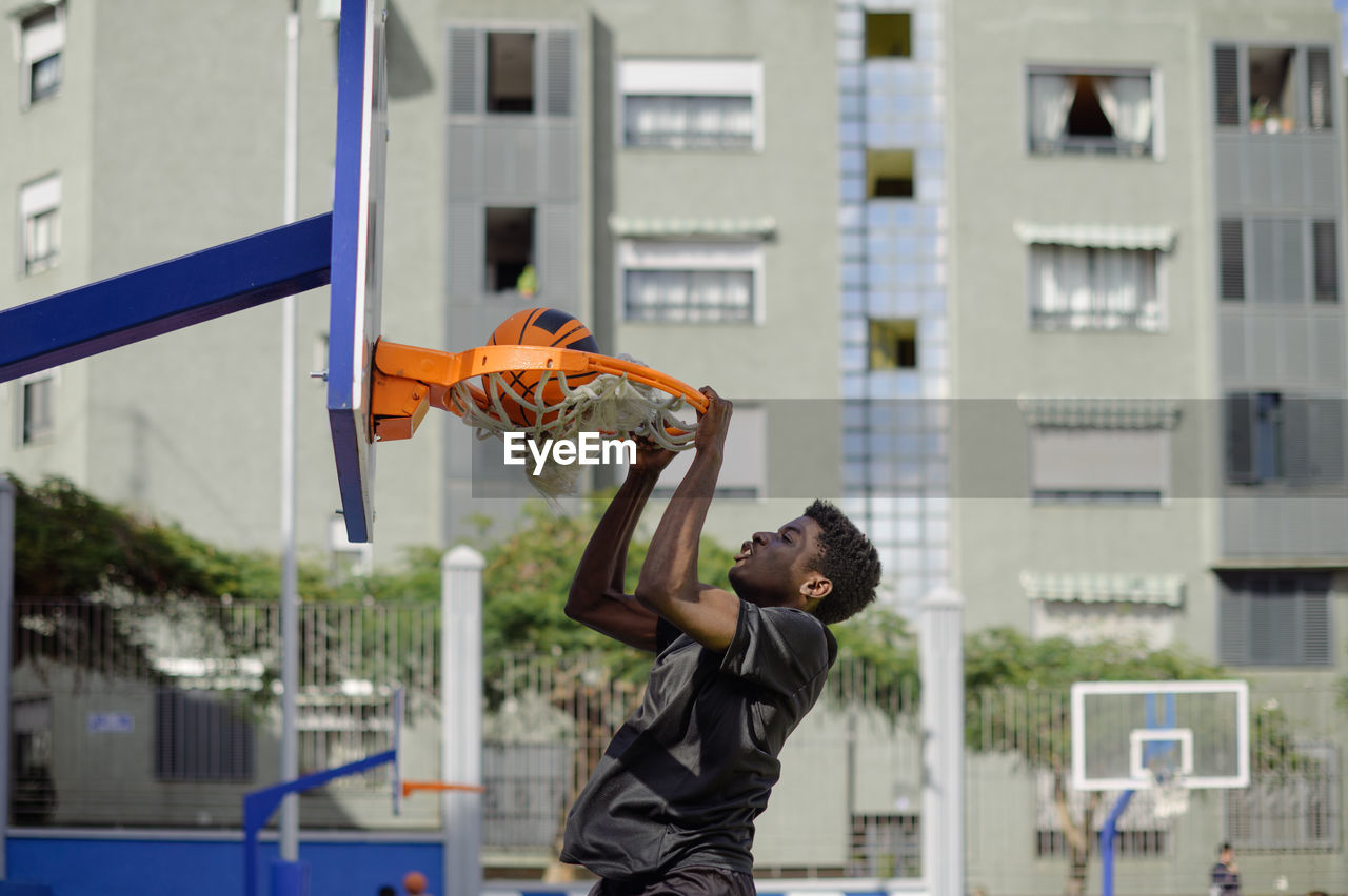 Low angle view of man playing basketball in city