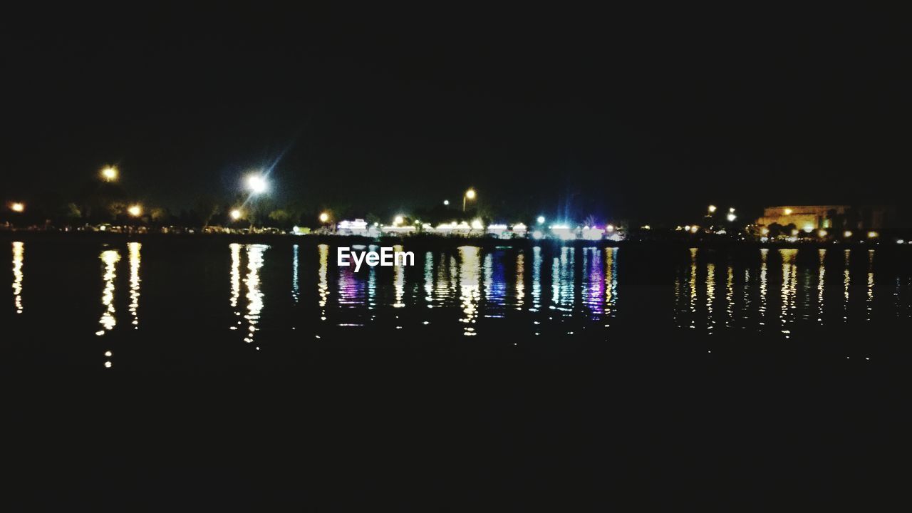 ILLUMINATED CITY BY RIVER AT NIGHT