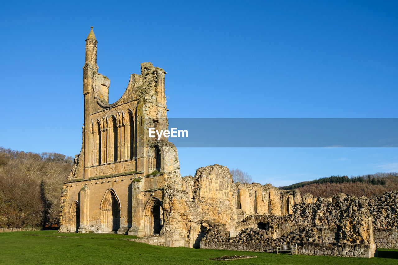 architecture, history, the past, sky, building, travel destinations, abbey, built structure, ancient, nature, historic site, blue, ruins, travel, grass, plant, old ruin, clear sky, building exterior, place of worship, religion, tourism, castle, no people, old, château, day, outdoors, land, landscape, landmark, sunny, tree, ancient civilization, medieval, belief, stone material, ruined, archaeology, spirituality, city