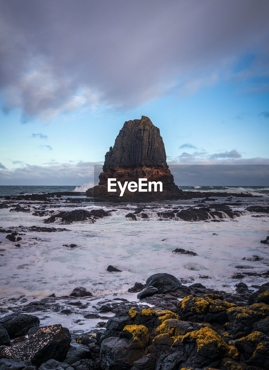 Rock formation on beach against sky