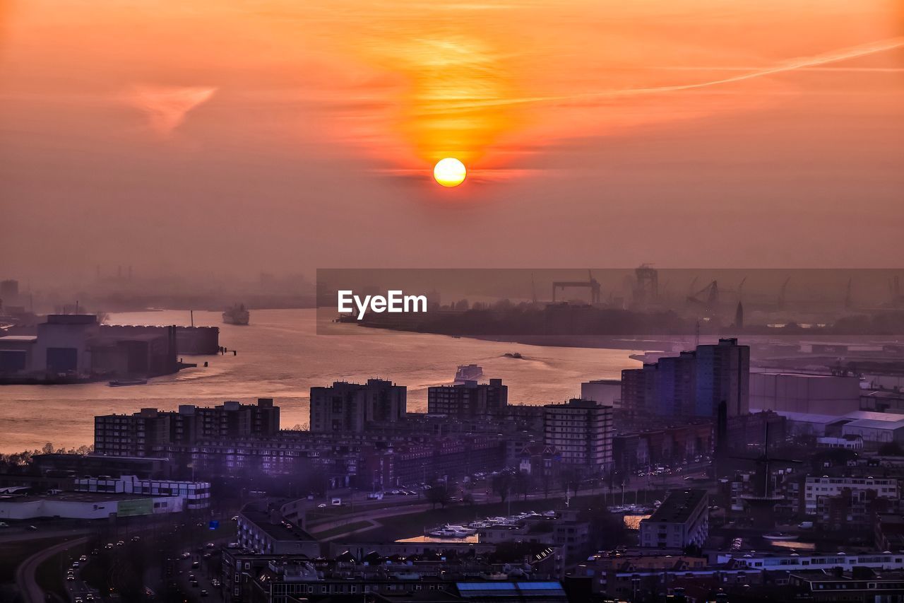 High angle view of cityscape by river during sunrise