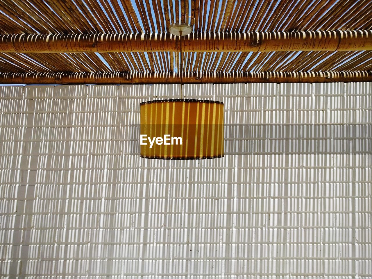 Empty room with lamp and sun coming through wooden panel roof casting pattern shadow