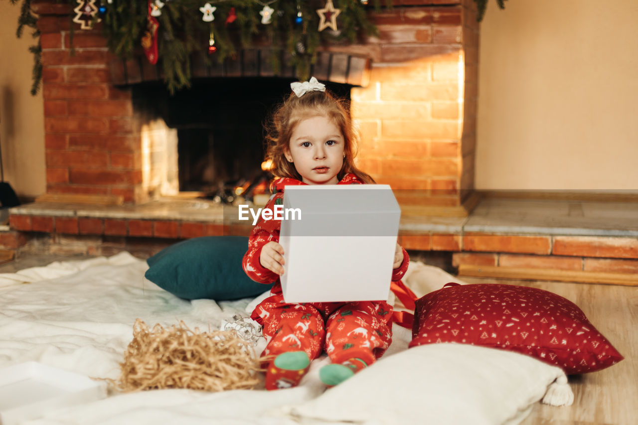 Little girl opens a christmas present near the christmas tree