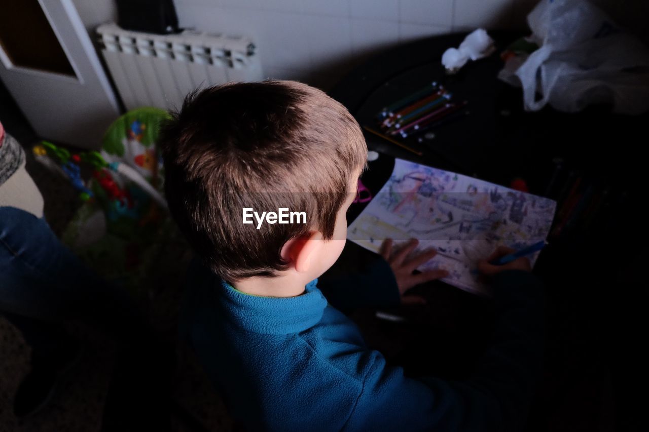 High angle view of boy drawing on table at home