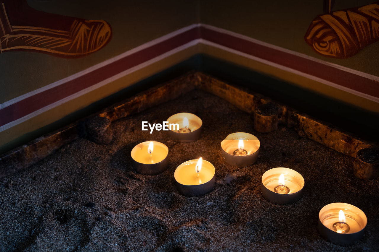 Church candles glowing with orange flames in a temple. symbols of faith and religion 