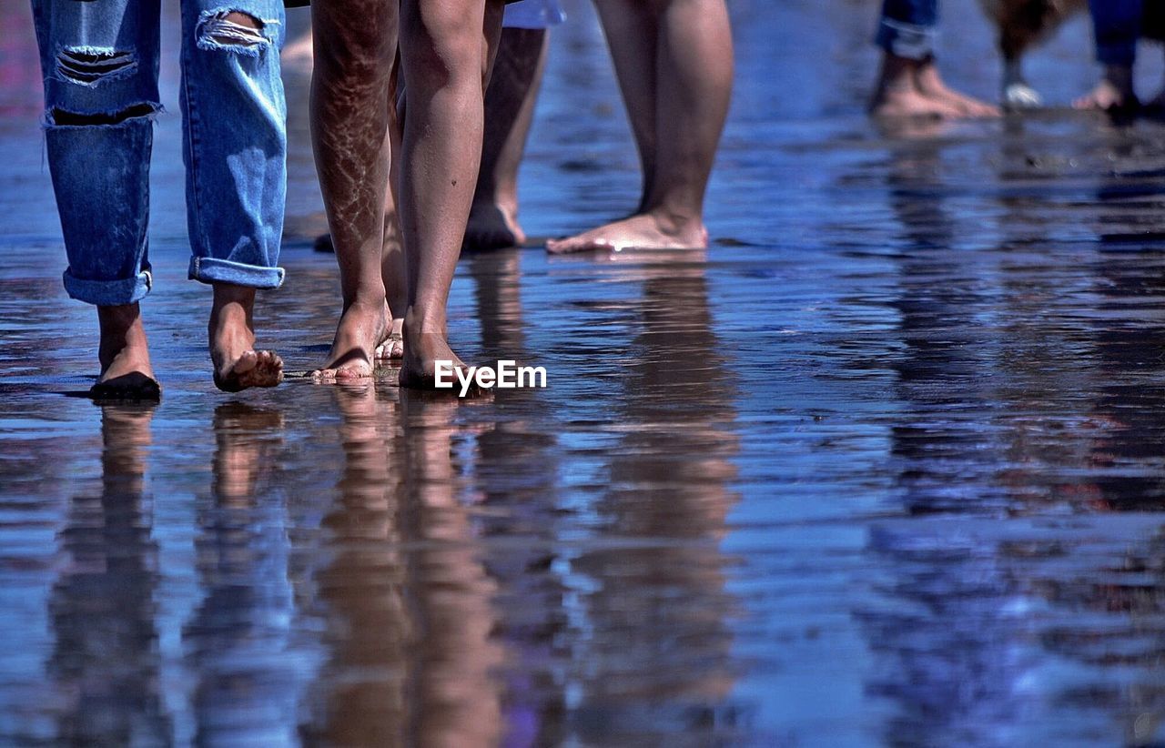 Low section of people walking at beach