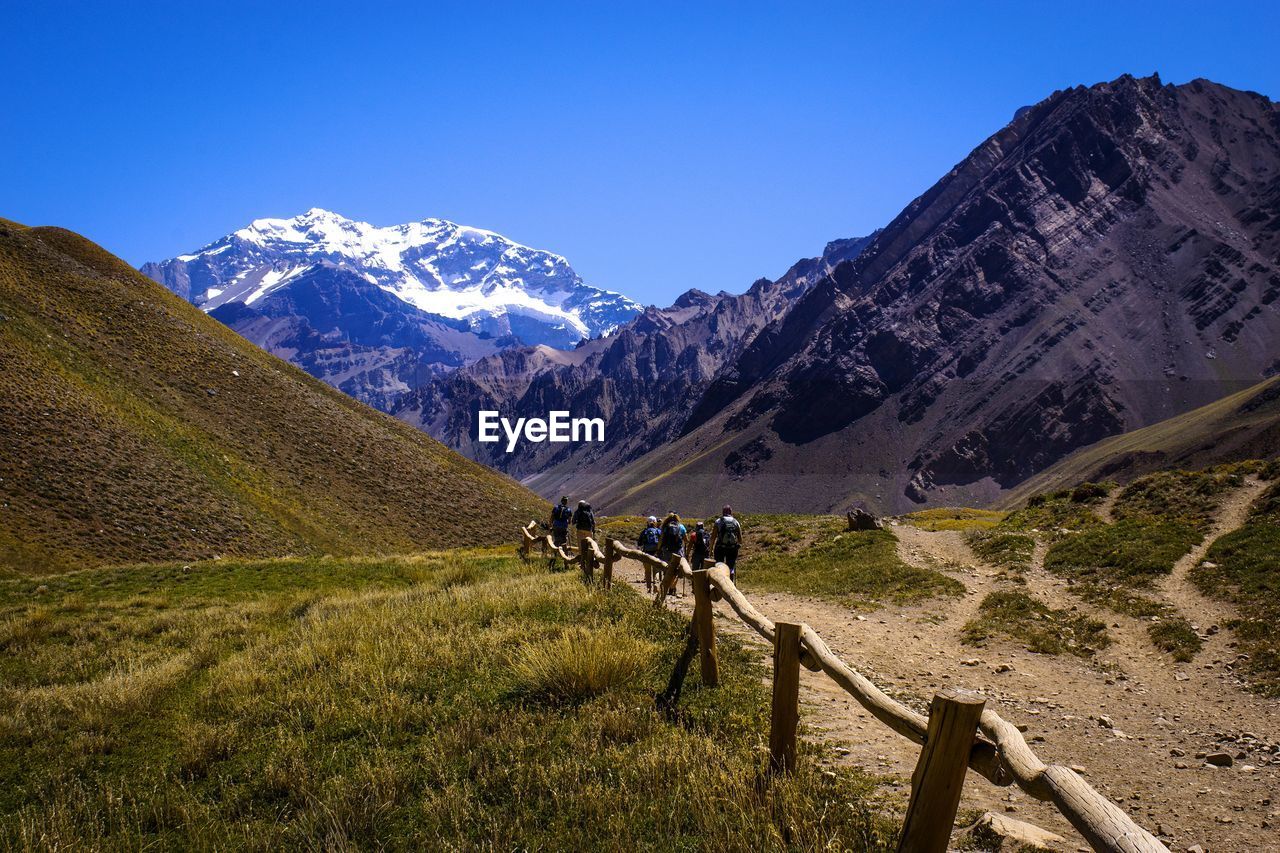 PEOPLE WALKING ON SNOWCAPPED MOUNTAIN AGAINST SKY