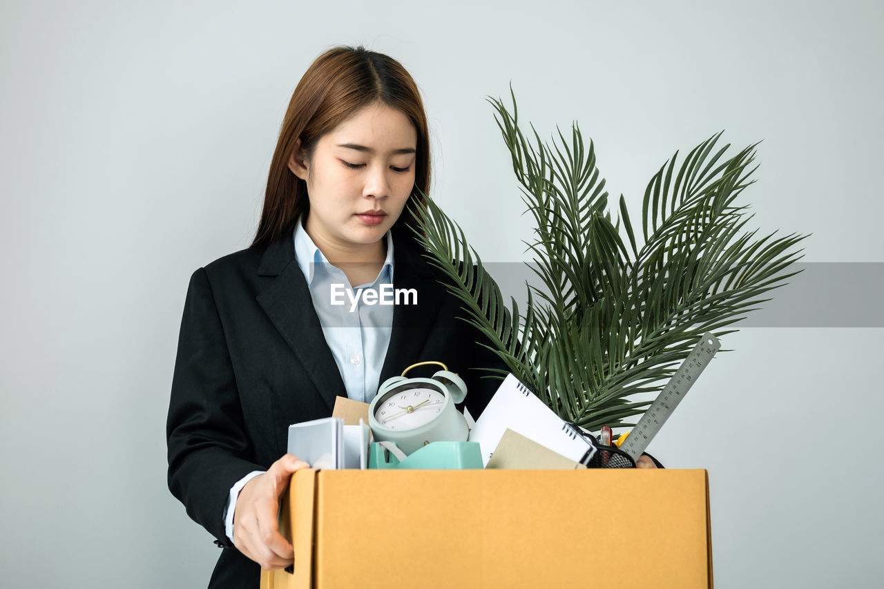 Portrait of businesswoman using laptop while standing against white background