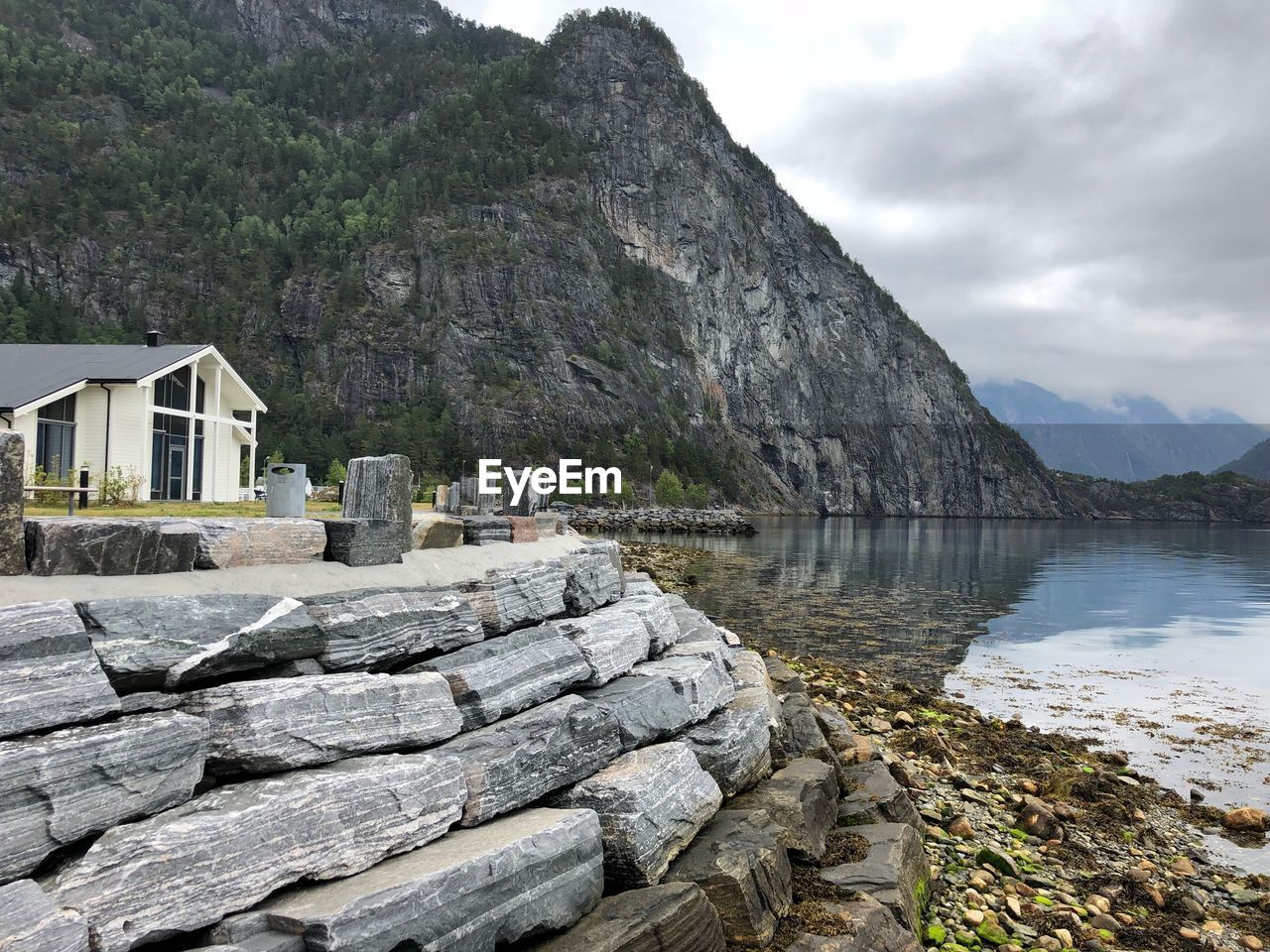 Scenic view of rocks by house and mountains against sky