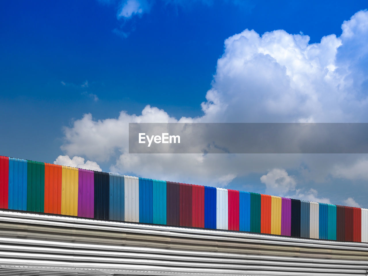 Colorful metal roof panel with blue sky and white clouds in the background.
