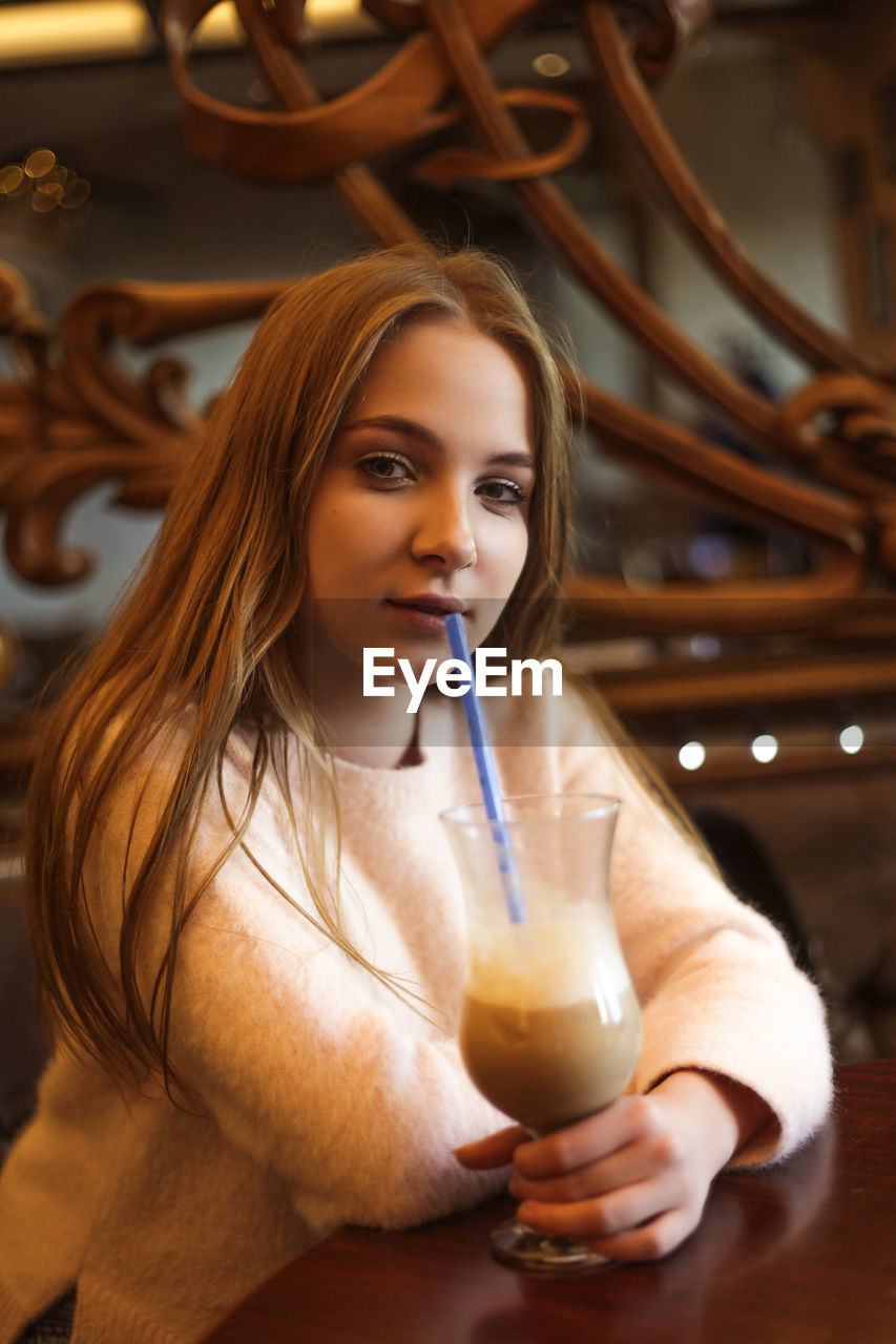 Beautiful young woman in a cafe with a glass of coffee with milk