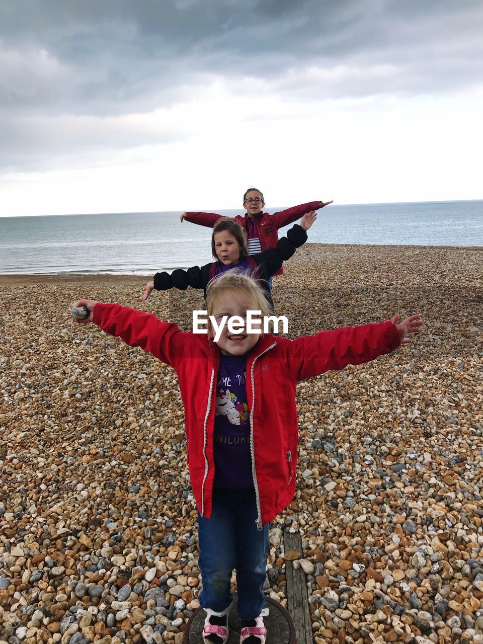 Sisters arms outstretched standing in row at beach