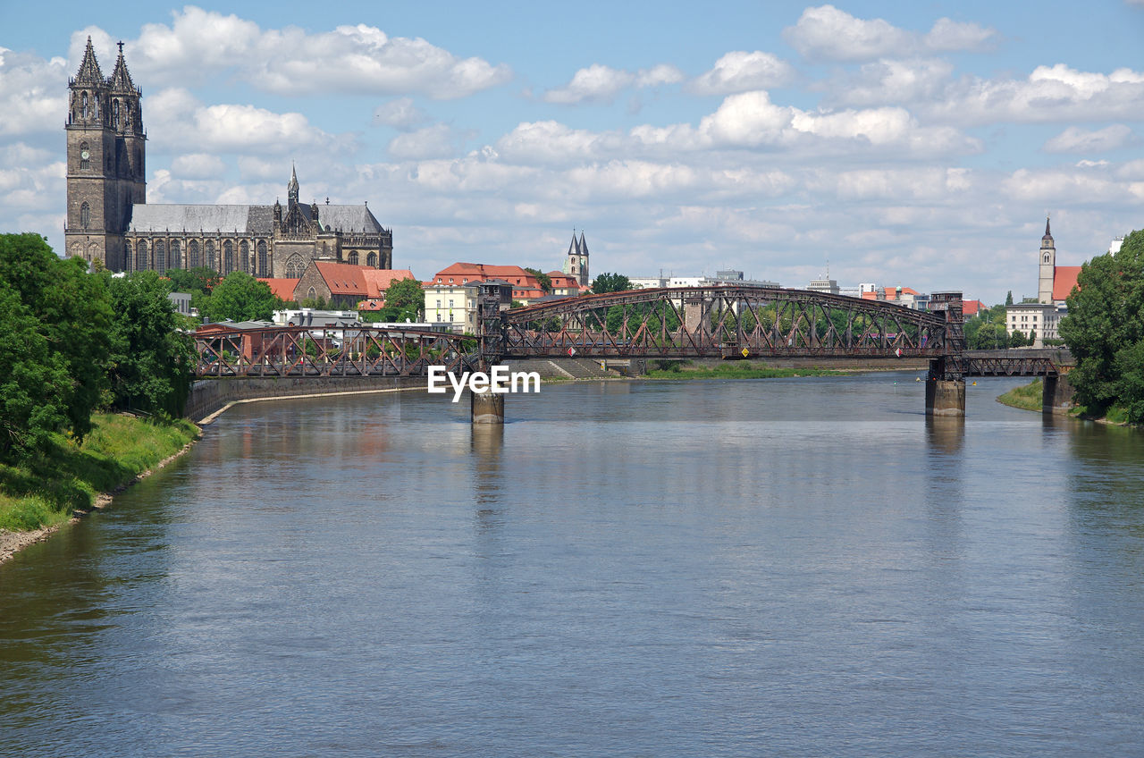 Bridge over river in town against sky