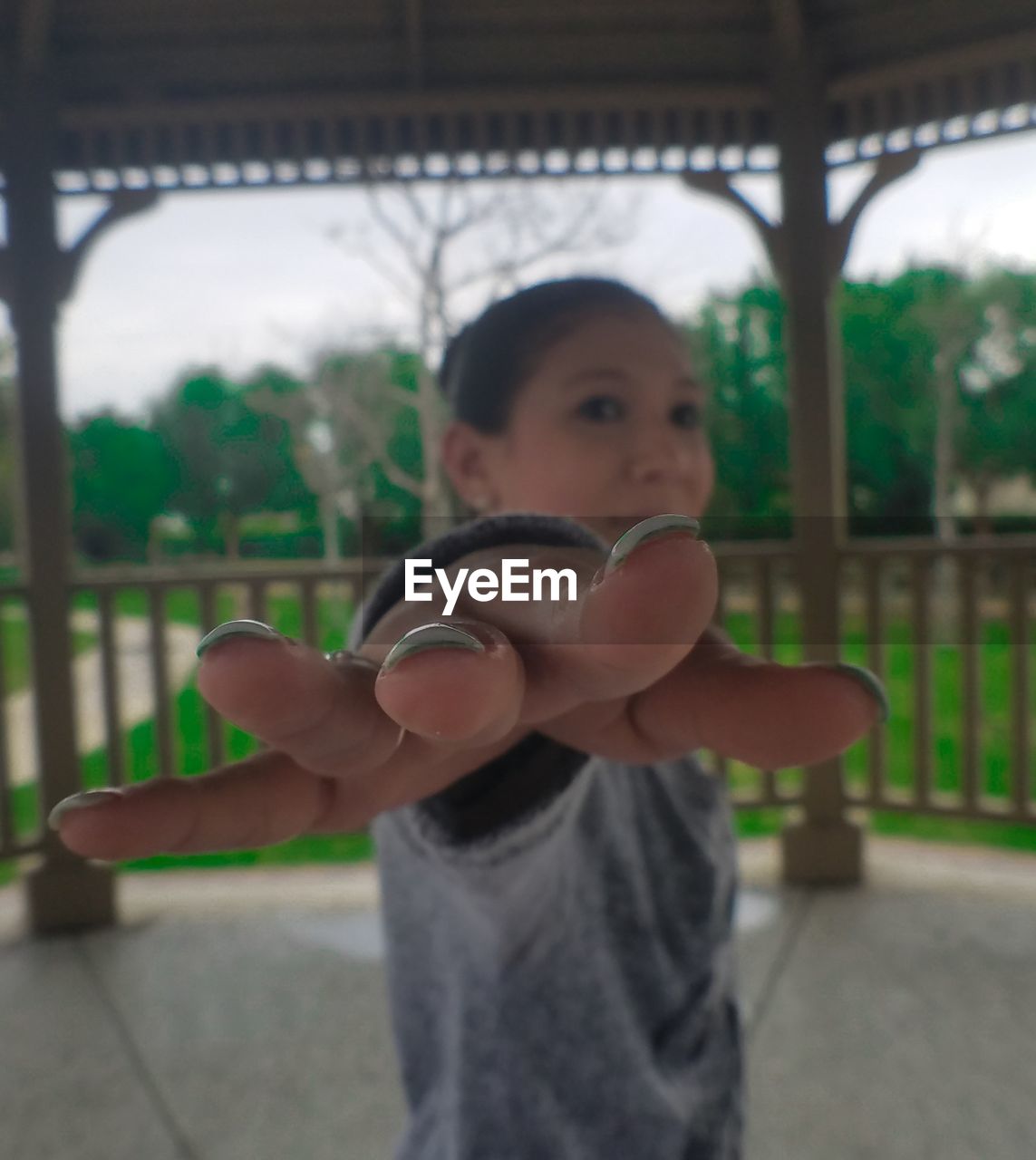 Portrait of woman showing fingers while standing at park