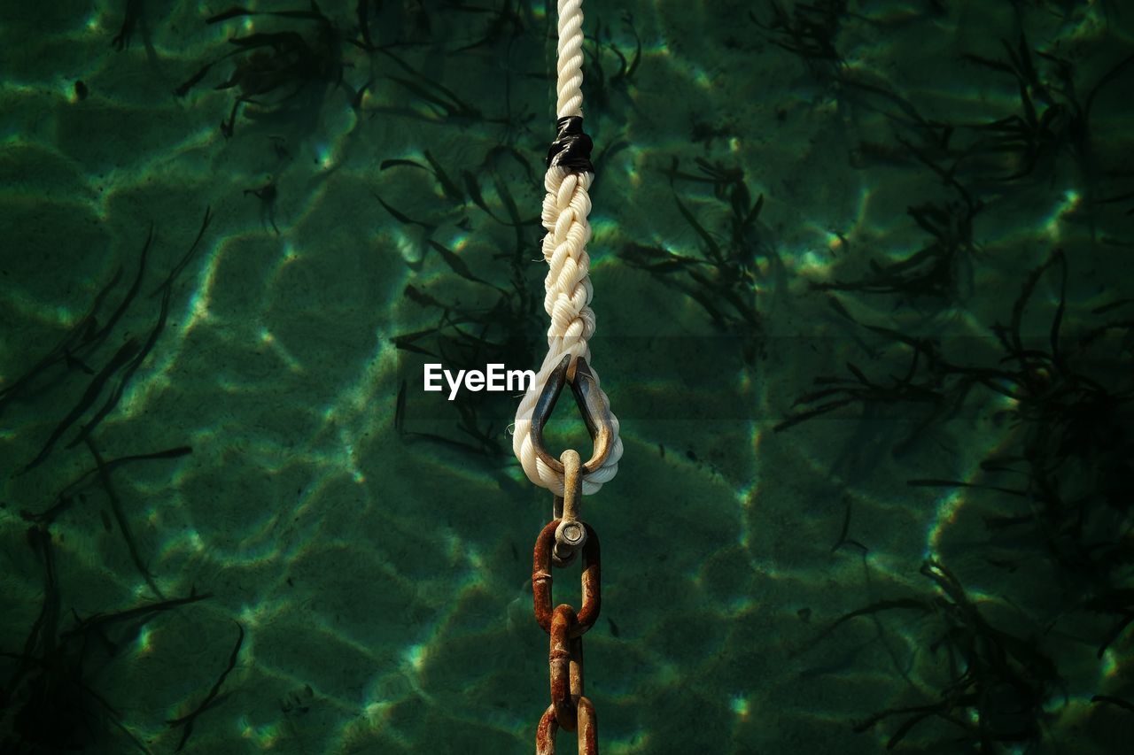 Close-up of rope connection with chain over lake