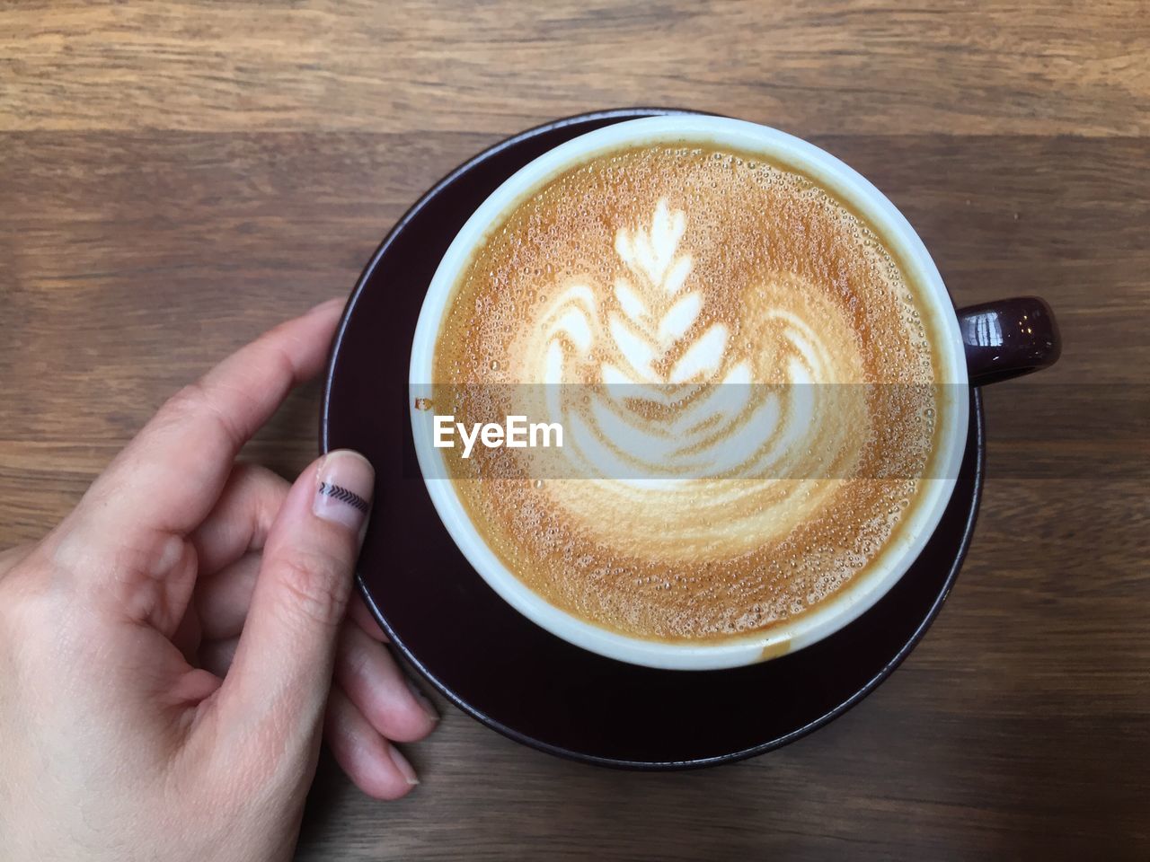 Cropped image of person holding coffee at table