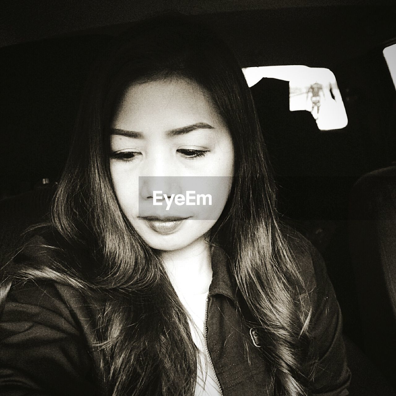 Beautiful young woman looking down while sitting in car