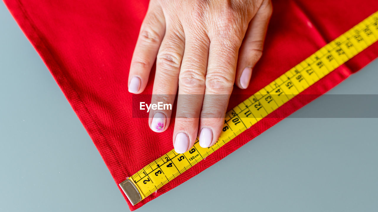 Cropped hand measuring textile with tape measure