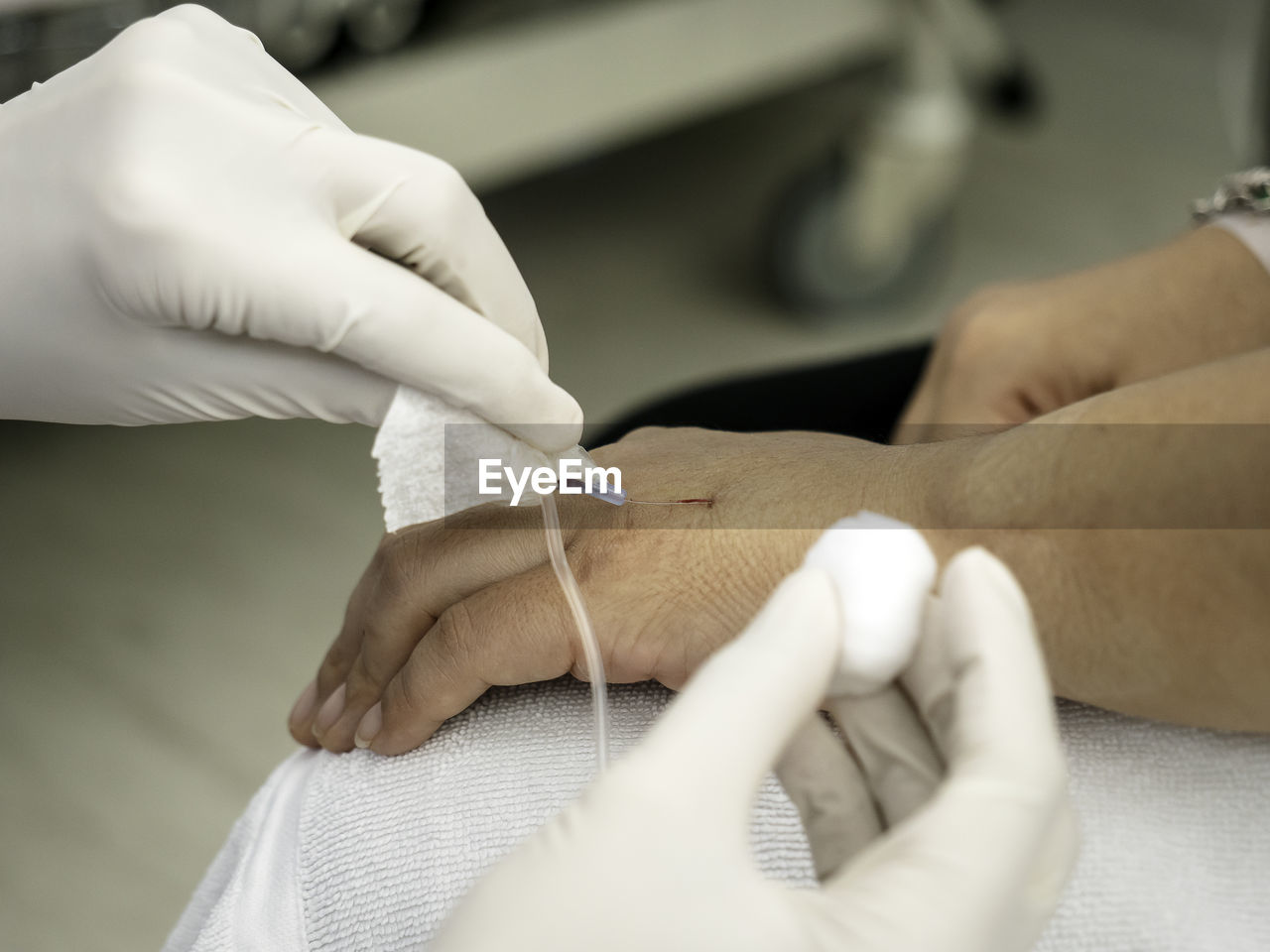 Cropped image of doctor removing medical equipment from patient hand in hospital