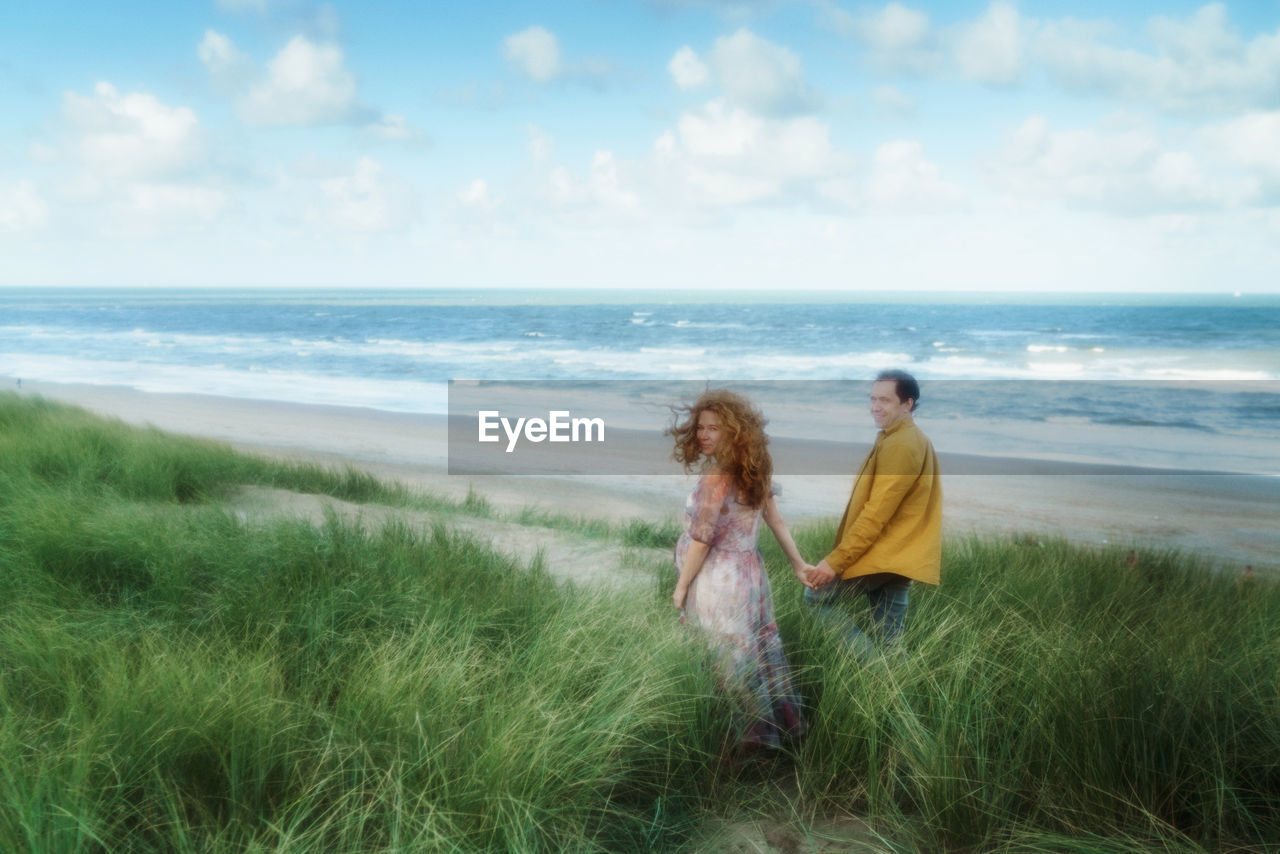 Couple enjoying at beach against sky