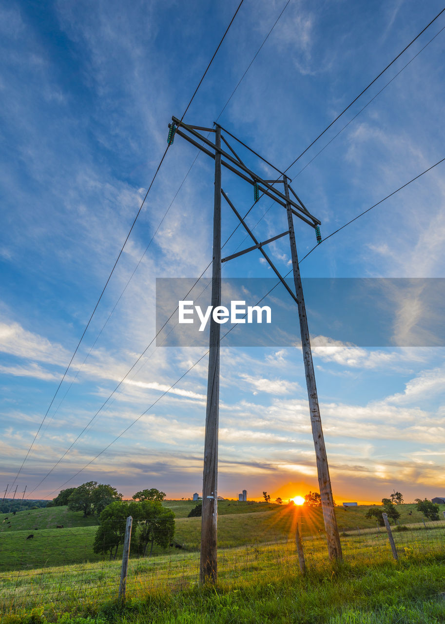 Low angle view of electricity pylon on field against sky