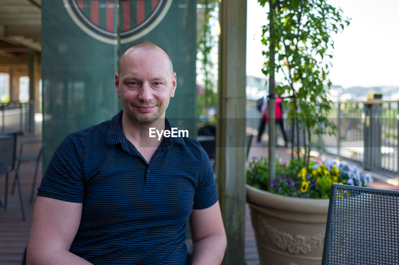 Portrait of smiling man sitting at sidewalk cafe