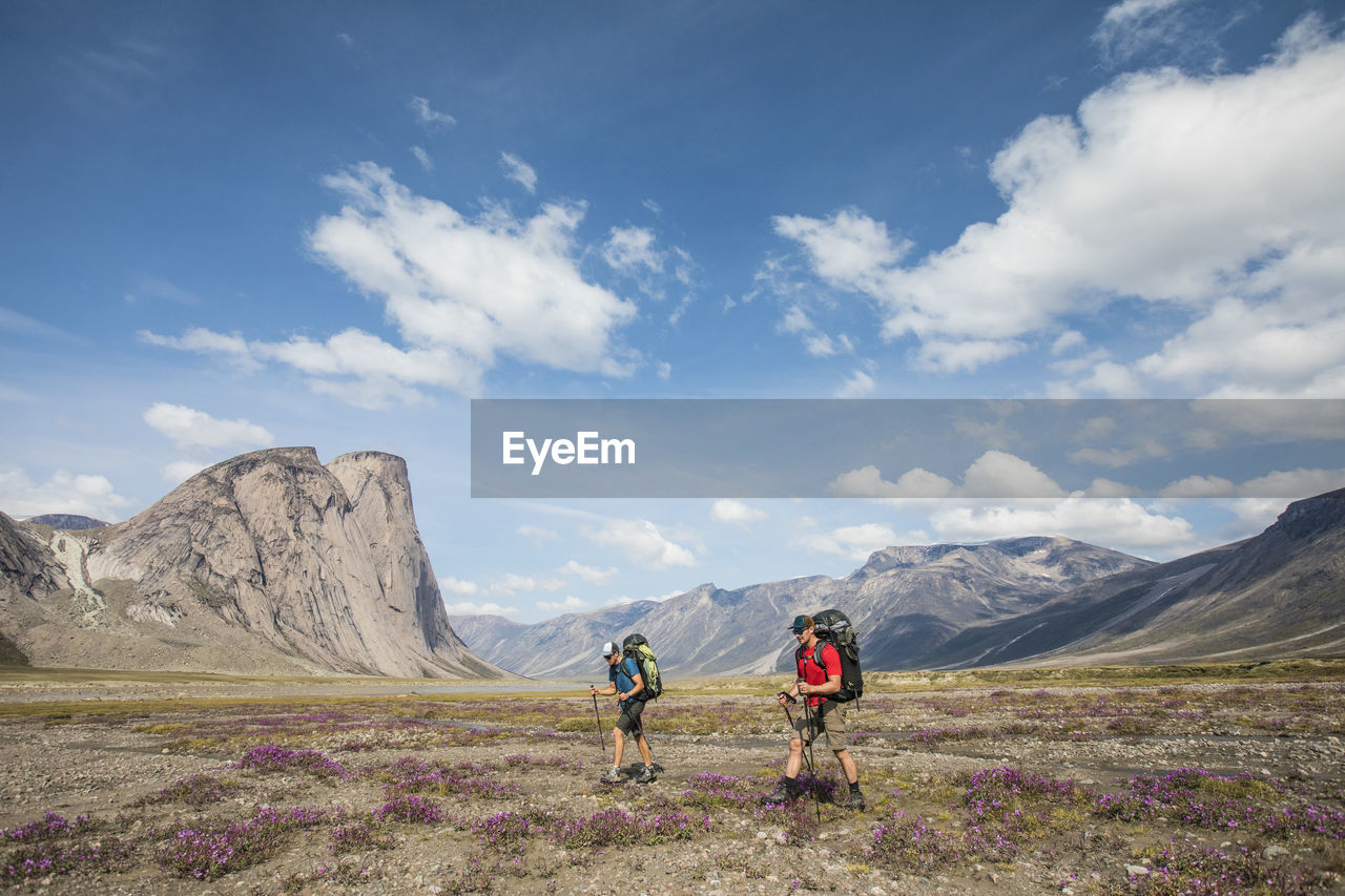 Two backpackers hiking through alpine meadow, akshayak pass