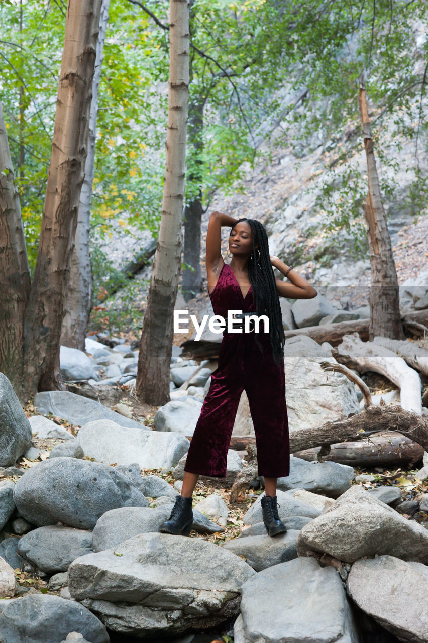 FULL LENGTH OF YOUNG WOMAN STANDING ON ROCK