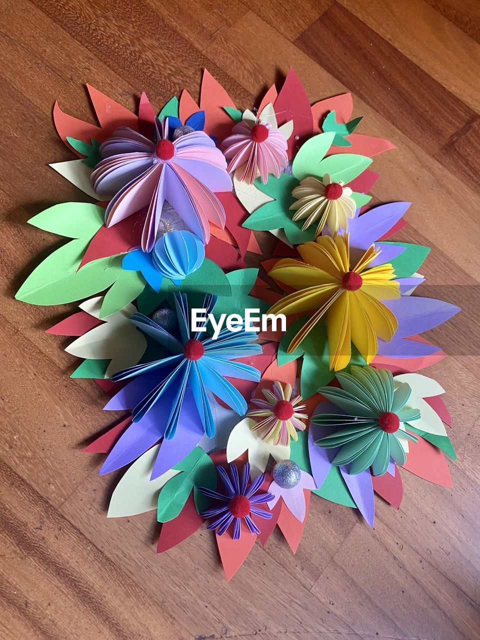 multi colored, wheel, origami, origami paper, flower, art, high angle view, art paper, creativity, wood, indoors, no people, petal, paper, craft, table, variation, still life, large group of objects, directly above, close-up, decoration, pattern