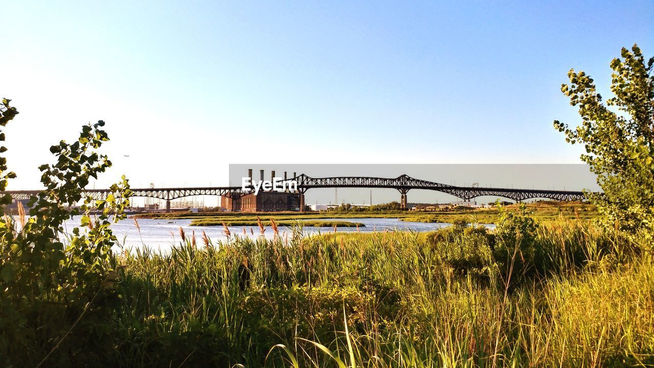 BRIDGE OVER RIVER BY FIELD AGAINST CLEAR SKY