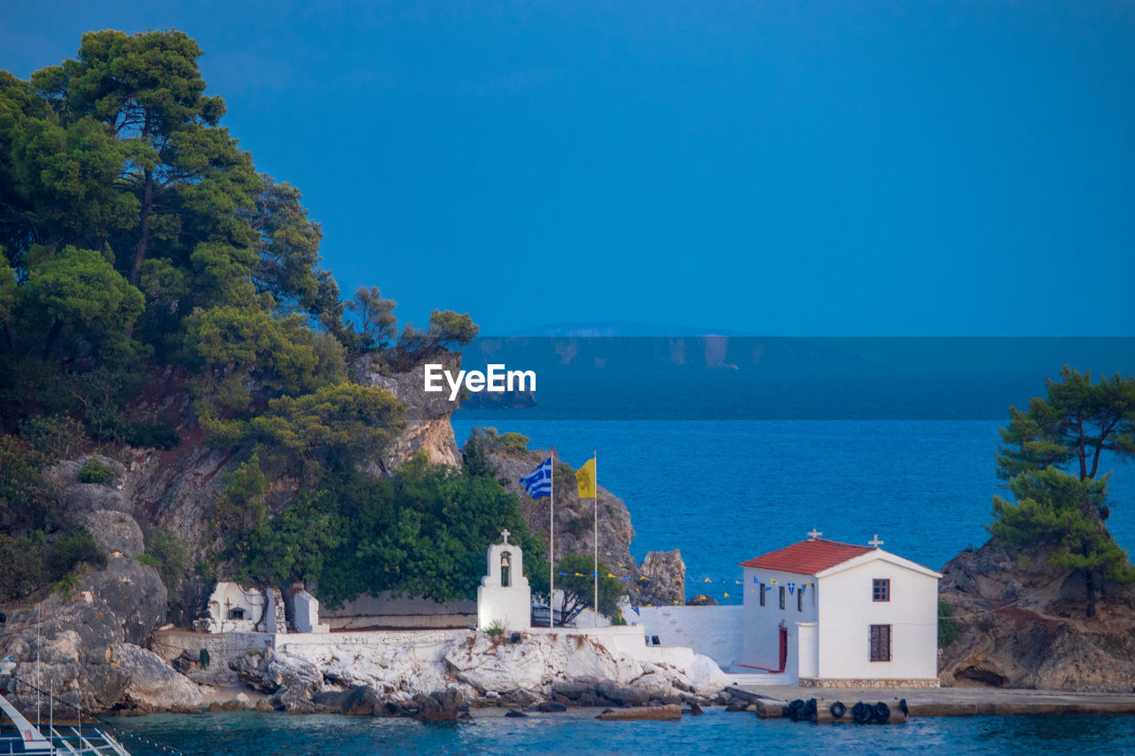 Buildings by sea against blue sky