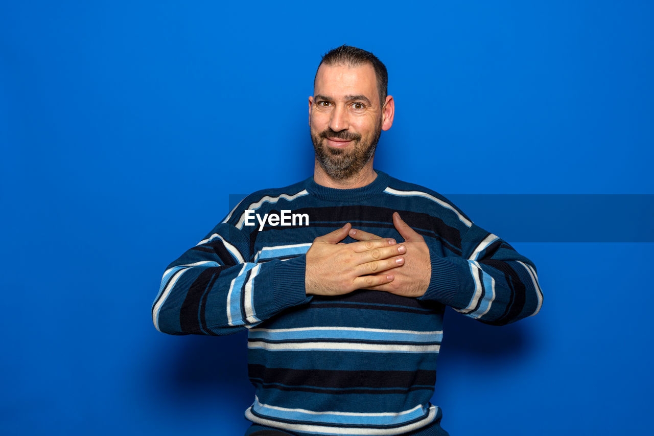 blue, one person, adult, studio shot, men, colored background, portrait, blue background, sports, athlete, looking at camera, indoors, waist up, strength, front view, exercising, sports clothing, muscular build, standing, facial hair, lifestyles, beard, emotion, clothing, young adult, person, arm, vitality, player, sports training, copy space, hand