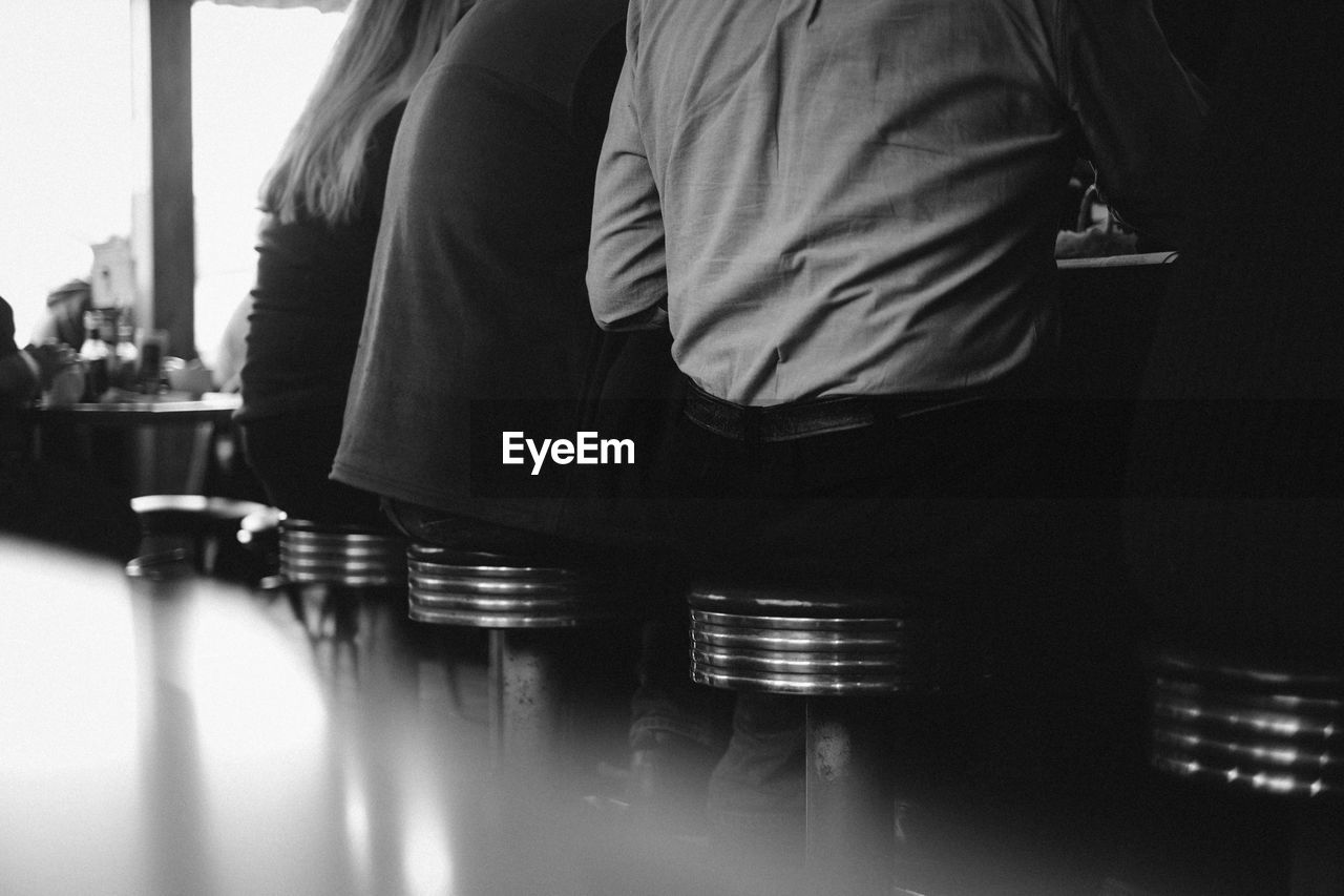 Midsection of people sitting on stool at bar