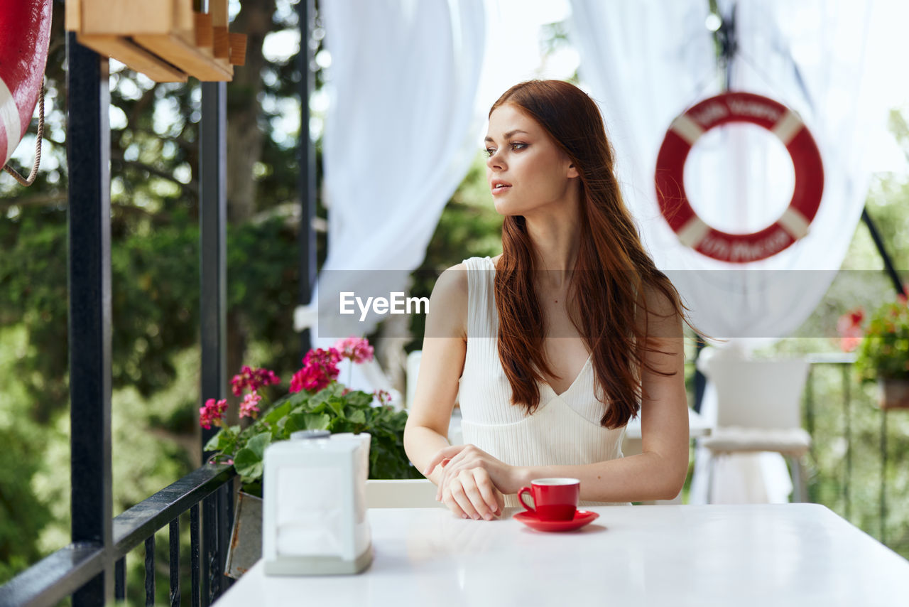 portrait of smiling young woman using mobile phone in restaurant