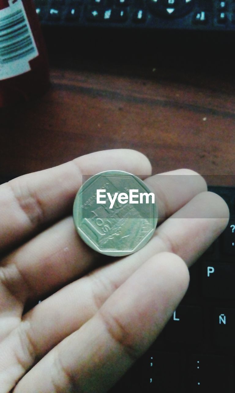 CLOSE-UP OF HAND HOLDING COINS IN THE DARK