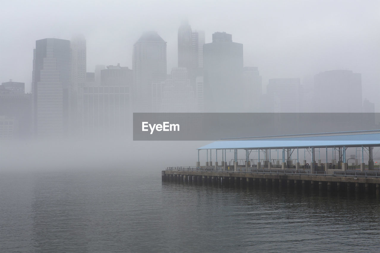 Pier by river in city during foggy weather