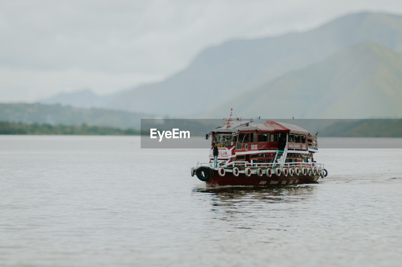 water, transportation, mountain, nautical vessel, mode of transportation, sea, ship, boat, vehicle, nature, shore, coast, day, scenics - nature, no people, travel, beauty in nature, bay, sky, watercraft, outdoors, tranquility, ferry, tranquil scene, mountain range, land, non-urban scene, environment, travel destinations, landscape