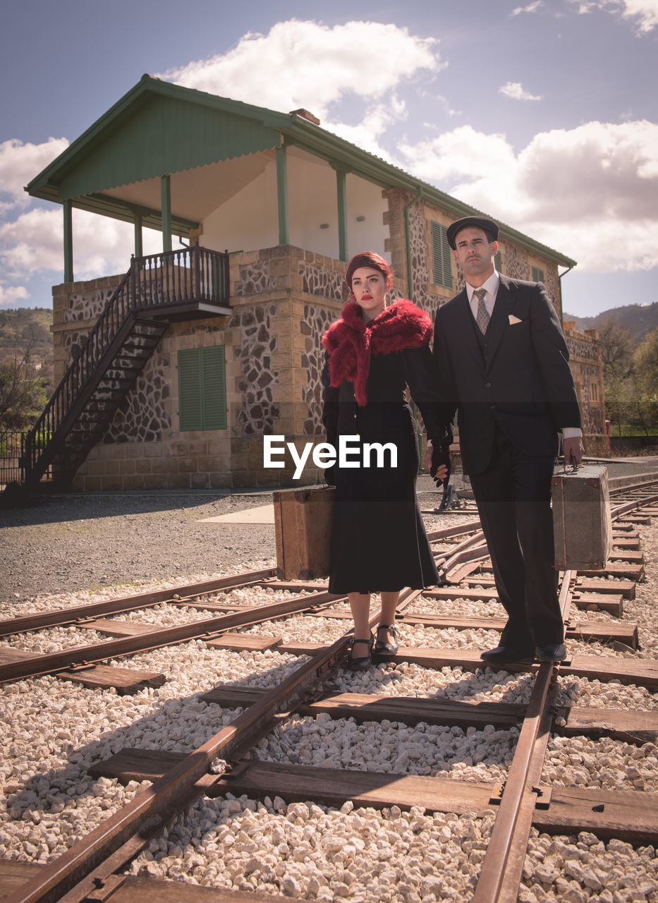 Couple with suitcase walking on railroad track